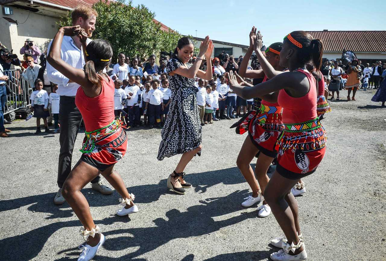 Meghan and Harry dance during their tour of Africa