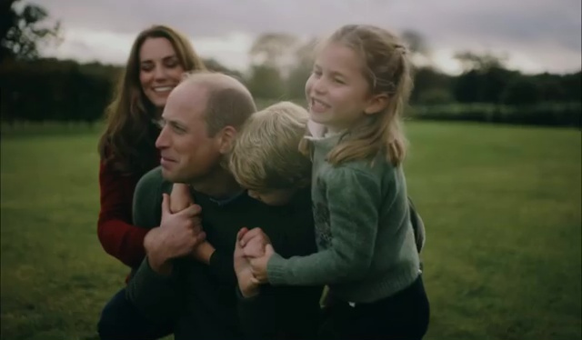 William smiling as Charlotte and George hug him as they play