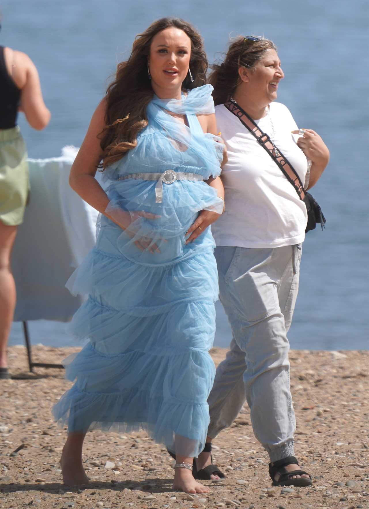 Charlotte Crosby cradles her baby bump in frilly blue dress as she films on the beach in Sunderland