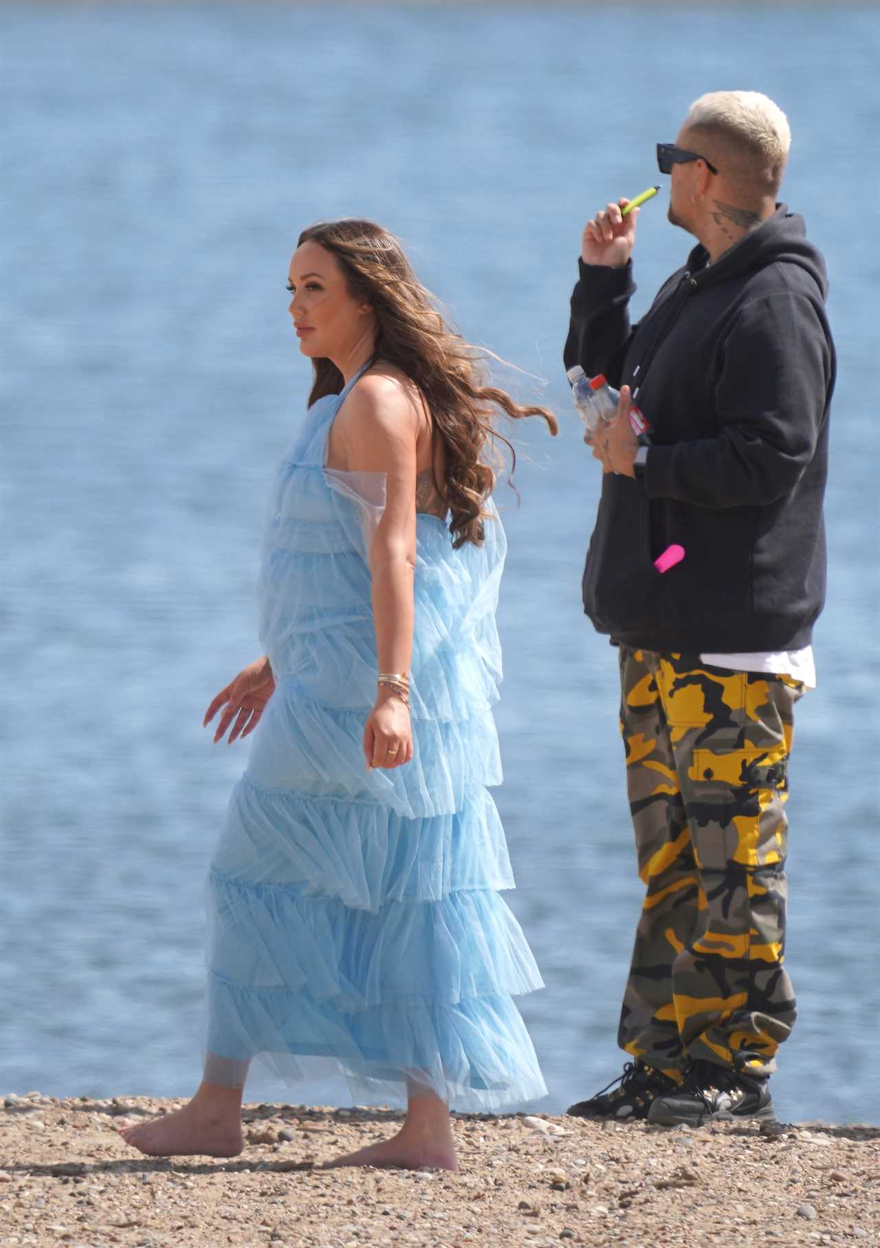 Charlotte Crosby cradles her baby bump in frilly blue dress as she films on the beach in Sunderland