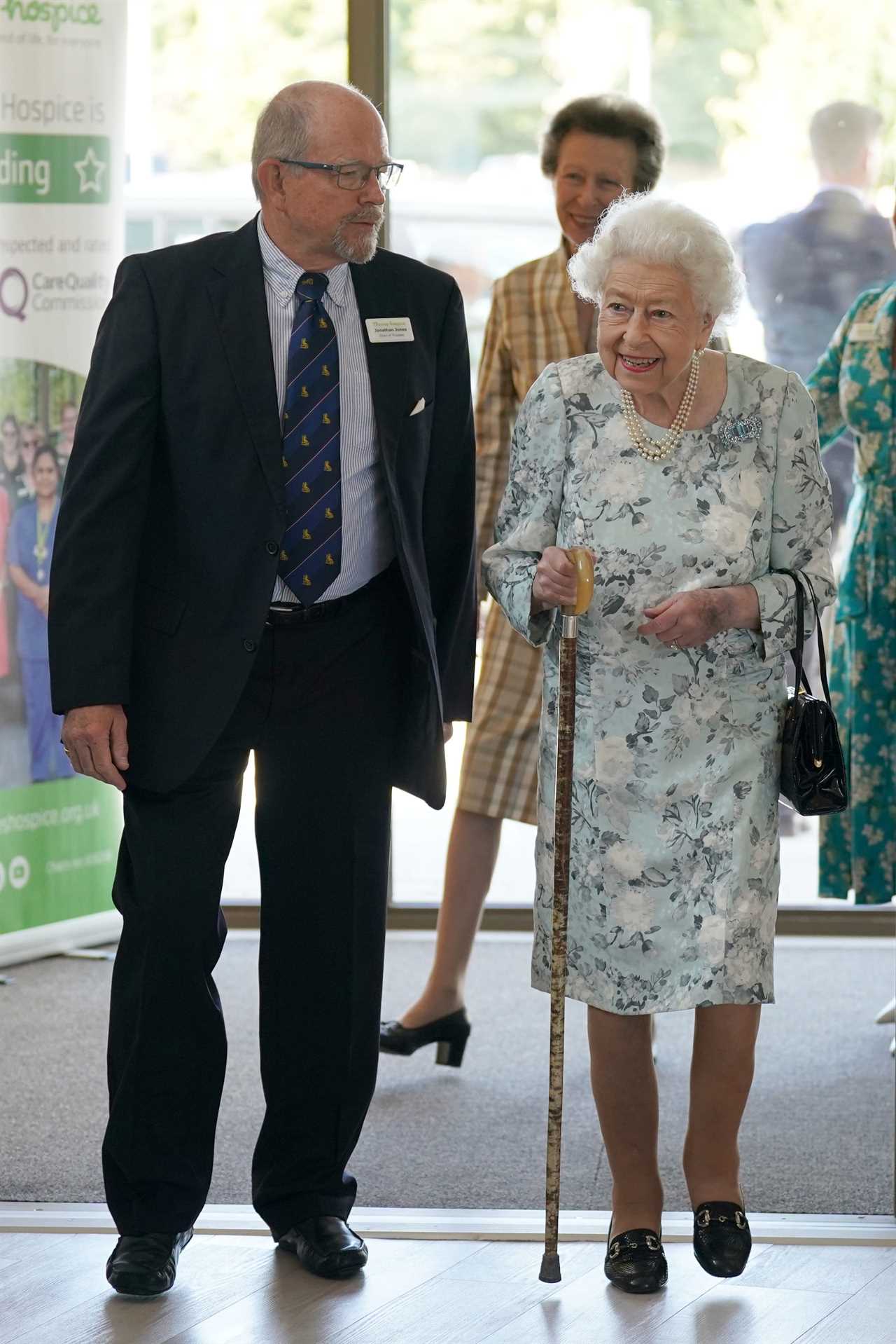 Queen, 96, beams in summer florals as she makes surprise visit to support hospice patients