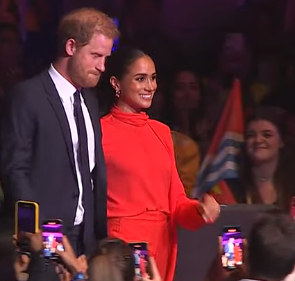 Meghan Markle beams as she takes to stage with Prince Harry and joins Bob Geldof ahead of speech