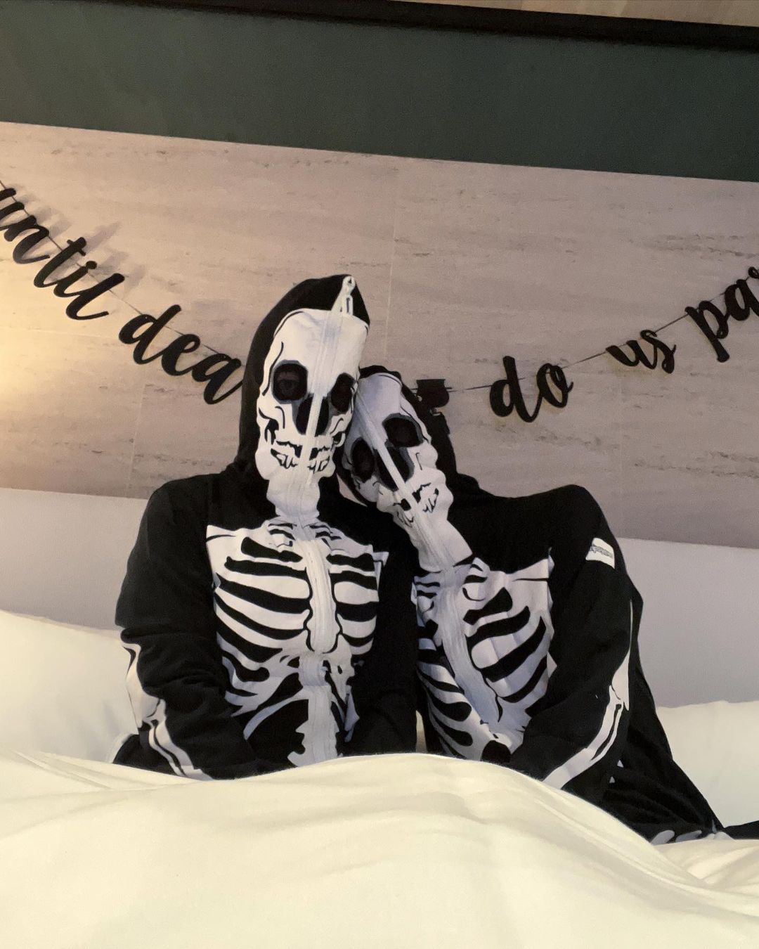 Kourtney Kardashian poses in bed with Travis Barker as they wear matching costumes after fans slam their Halloween decor