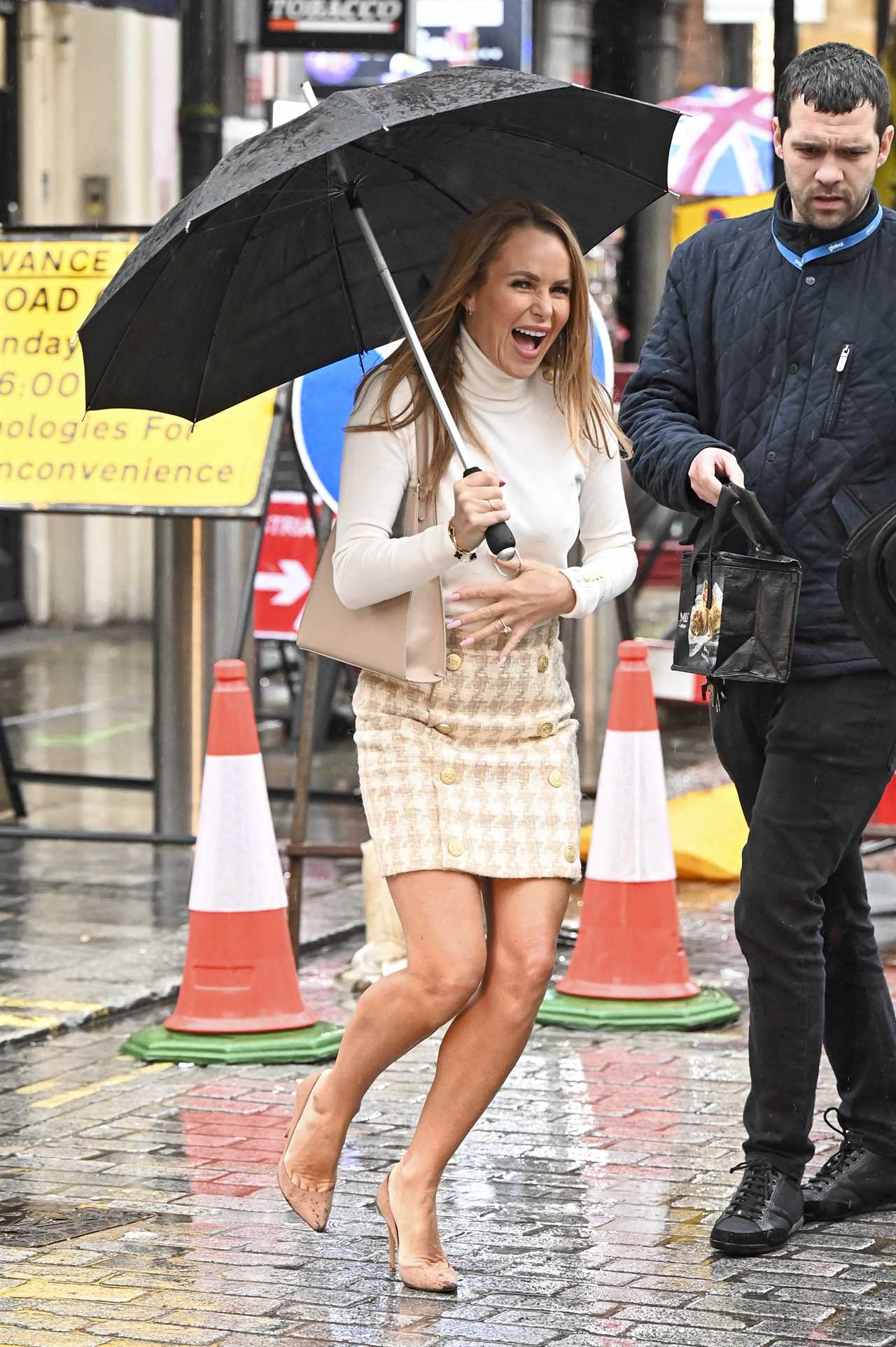 Amanda Holden goes braless and grabs her chest as she’s caught in the rain in London