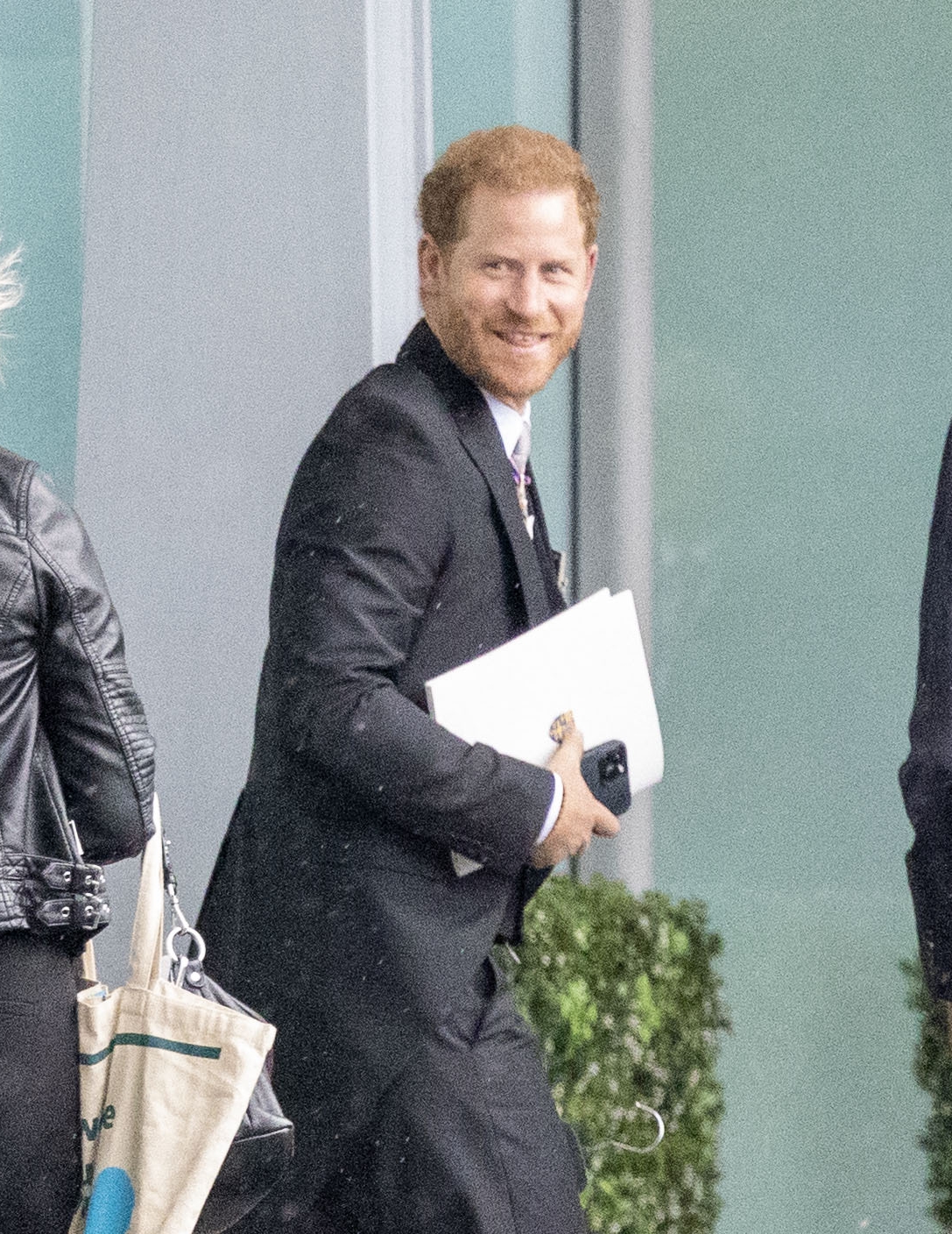 Prince Harry grins at Heathrow before jetting to LA just an hour after coronation as his family wave on Palace balcony