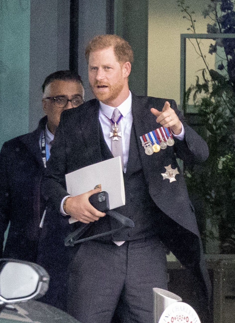 Prince Harry grins at Heathrow before jetting to LA just an hour after coronation as his family wave on Palace balcony