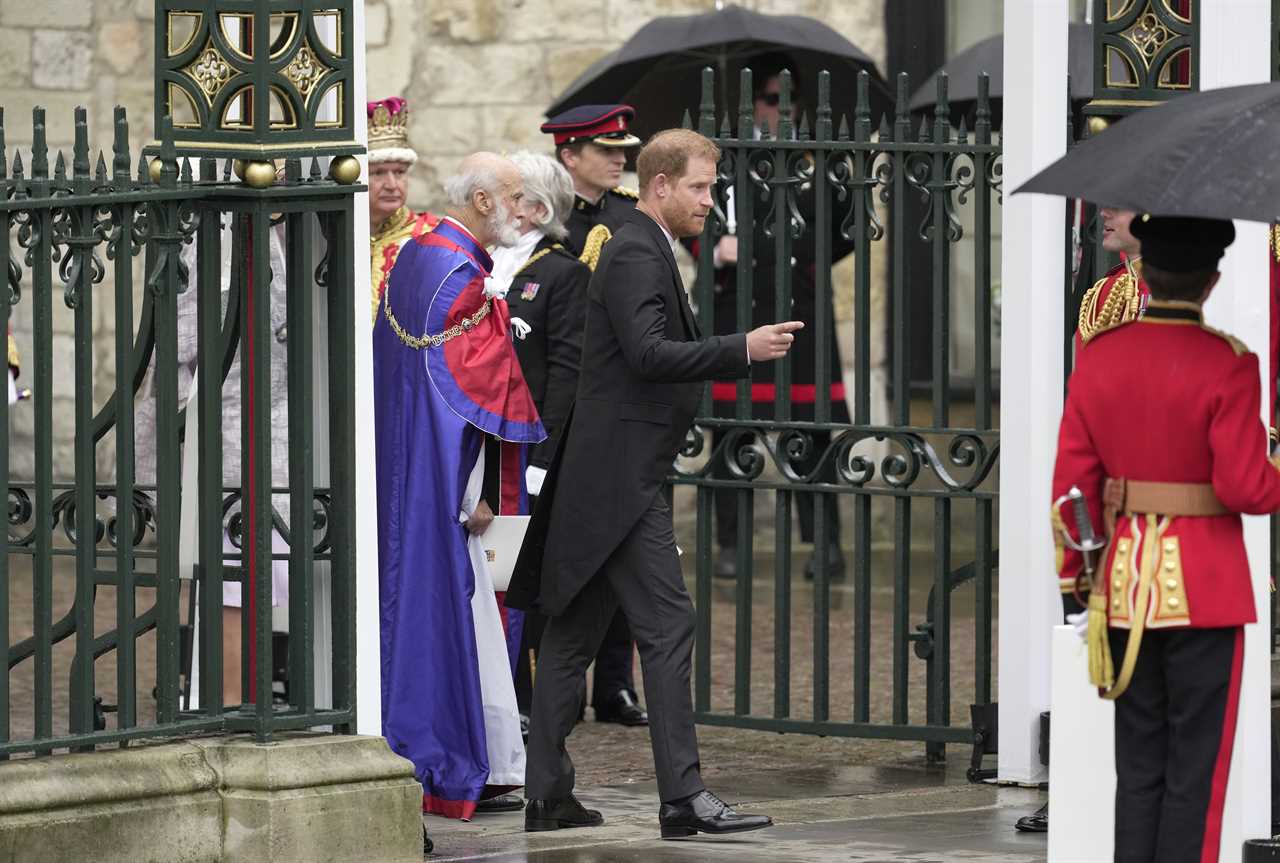 Prince Harry grins at Heathrow before jetting to LA just an hour after coronation as his family wave on Palace balcony