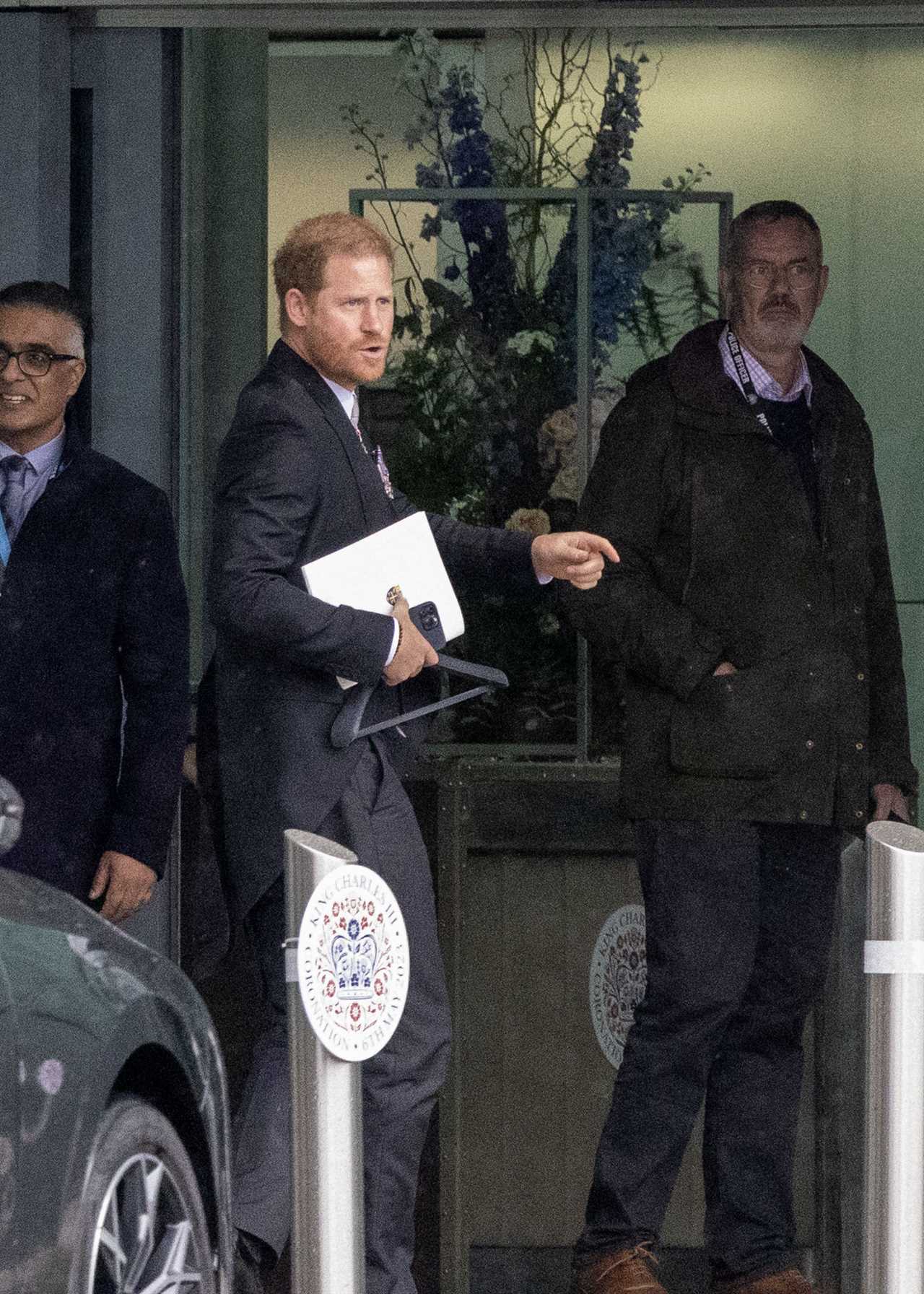 Prince Harry grins at Heathrow before jetting to LA just an hour after coronation as his family wave on Palace balcony