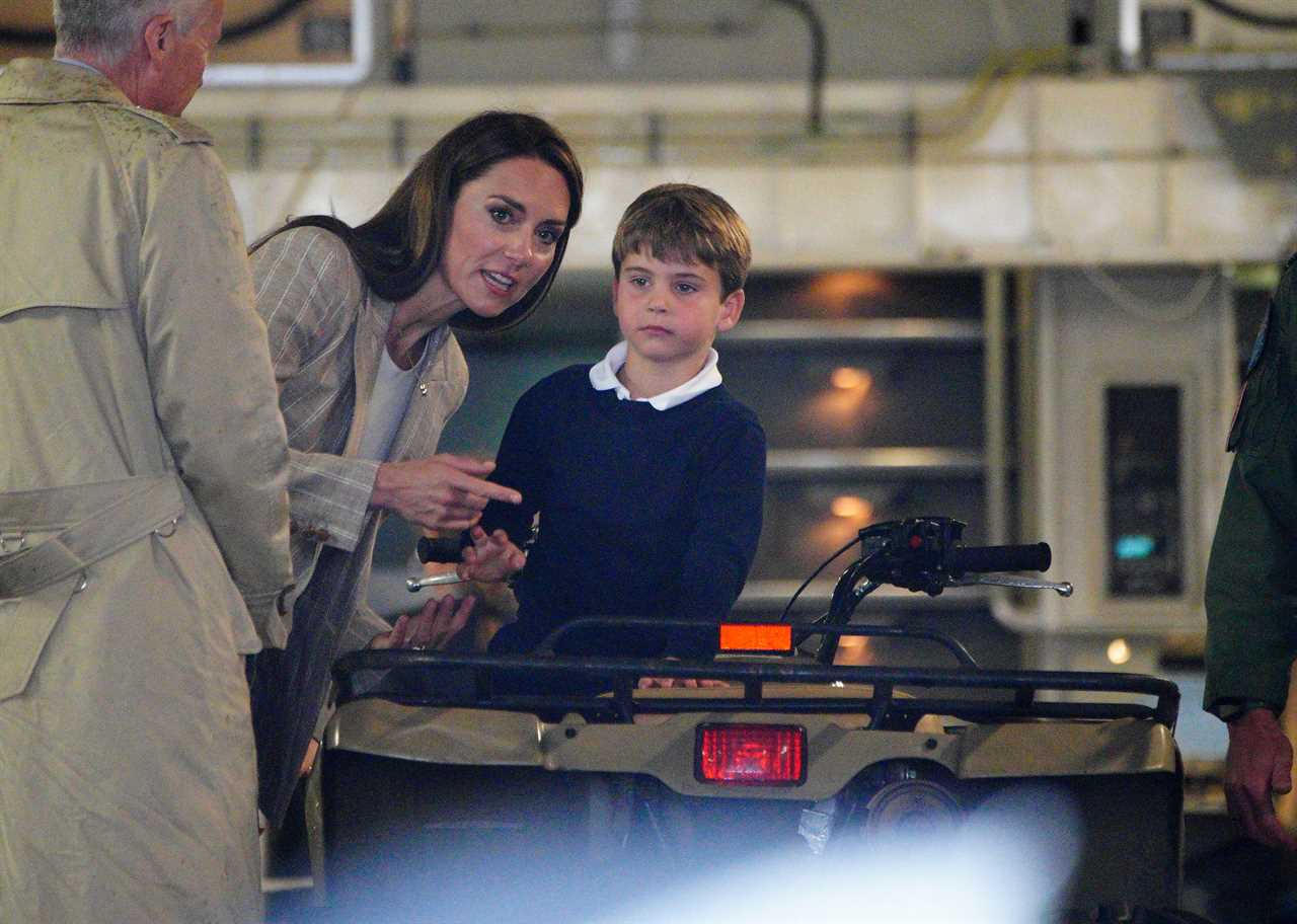 Prince Louis gives a shy wave as Kate helps him climb onto a quad bike during family day out with siblings at air show