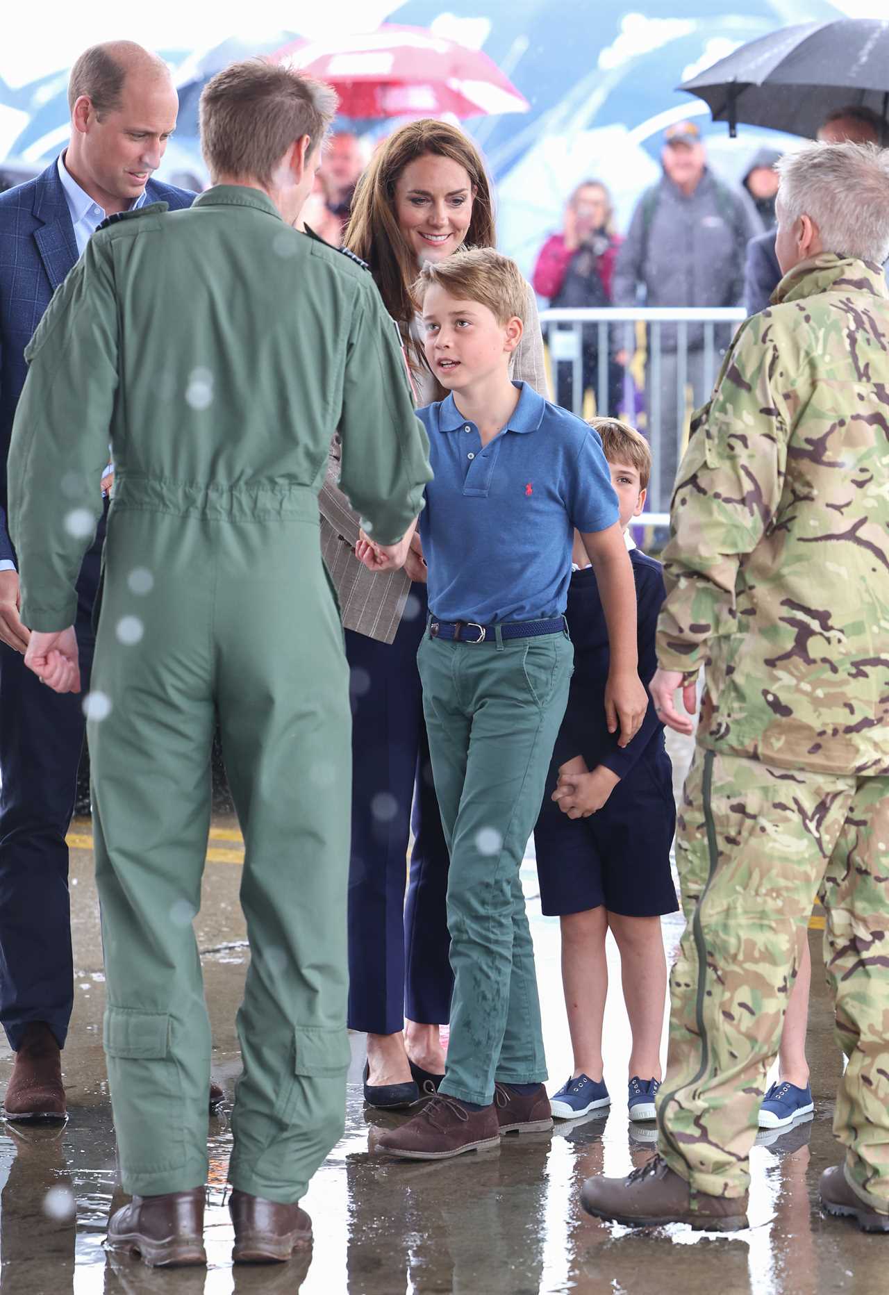 Prince Louis gives a shy wave as Kate helps him climb onto a quad bike during family day out with siblings at air show