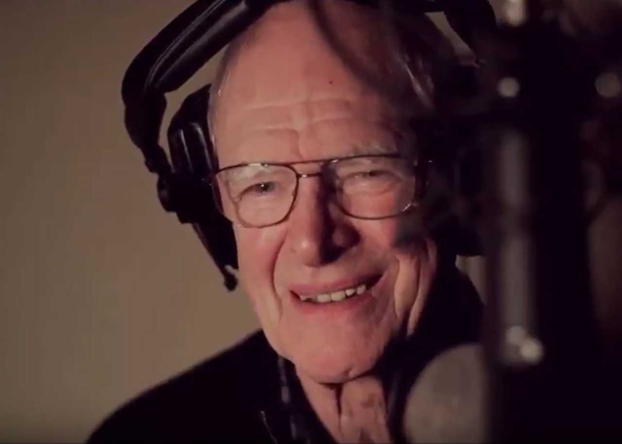 a man wearing glasses and headphones is smiling in front of a microphone