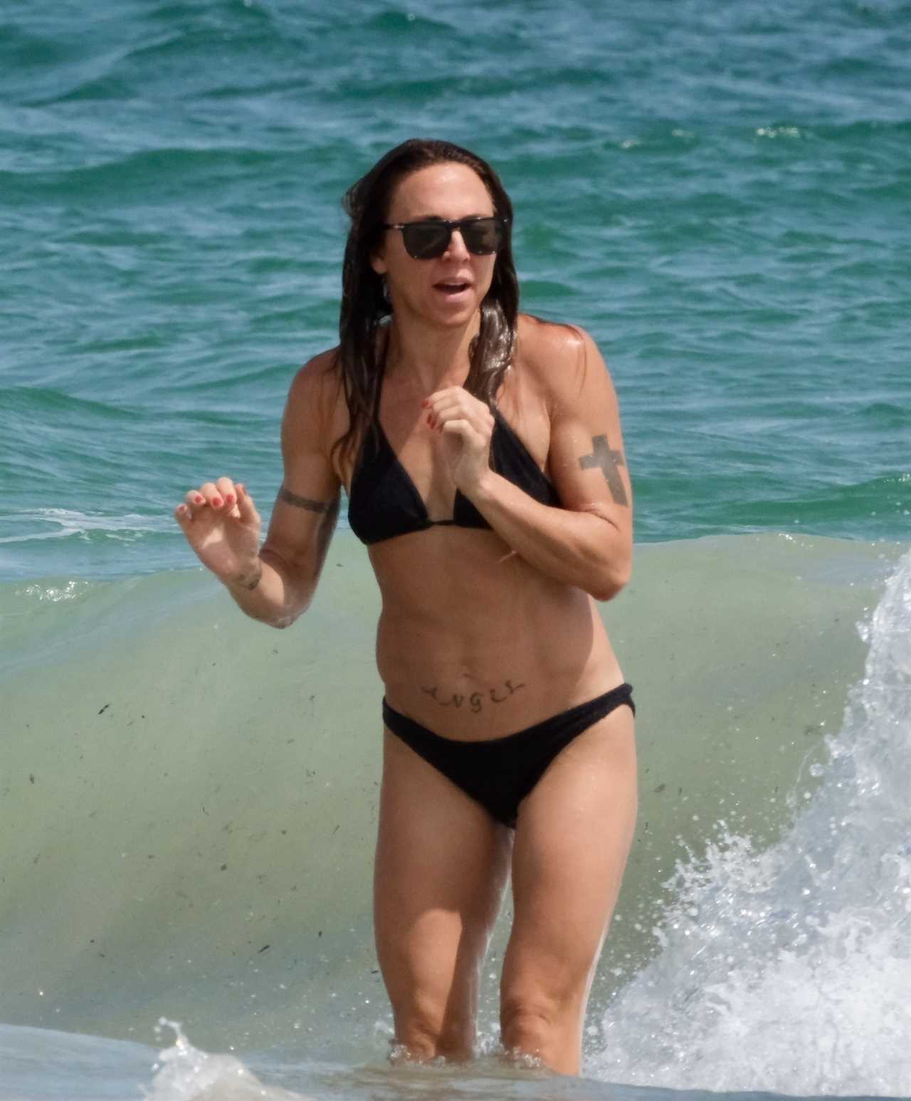 Mel C flaunts washboard abs in black bikini as she hits the beach in Ibiza