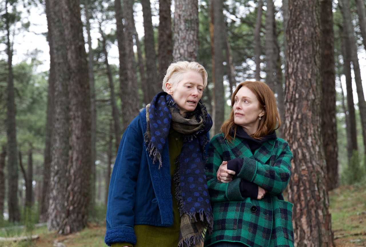 two women standing next to each other in a forest