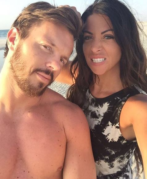 a man and a woman are posing for a picture on the beach .