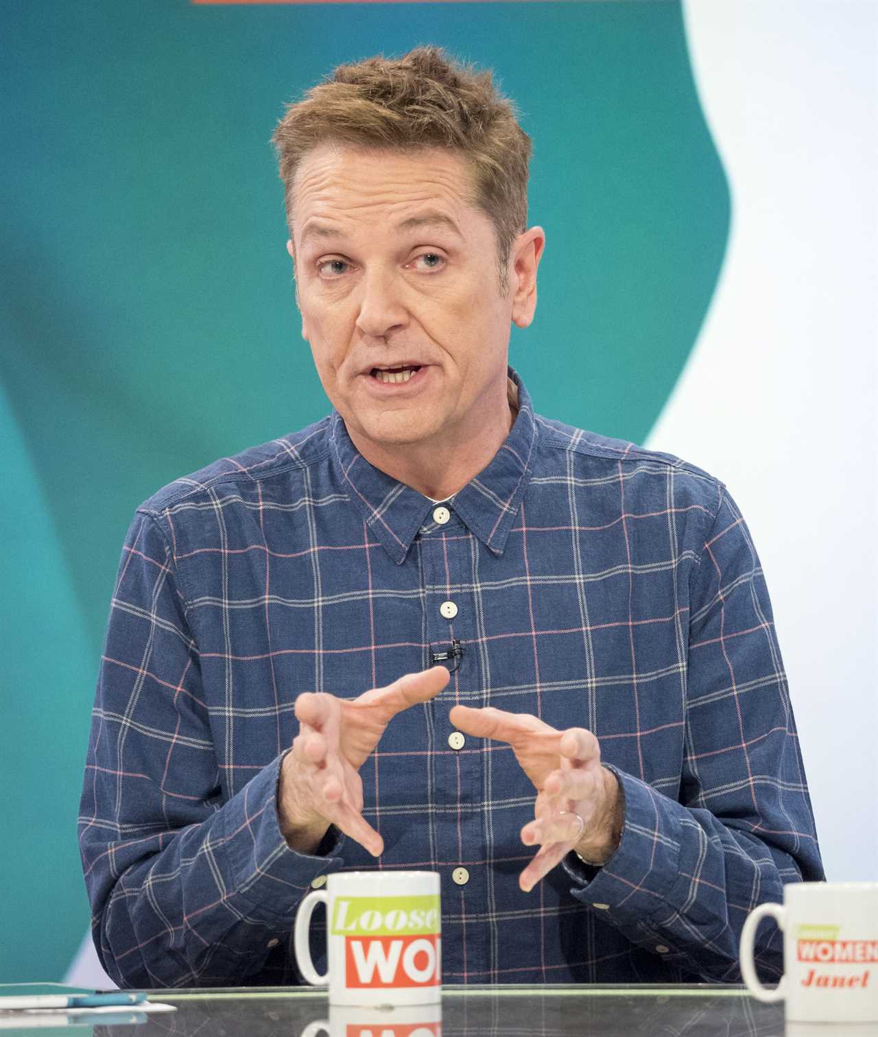 a man in a plaid shirt sits in front of a loose women mug