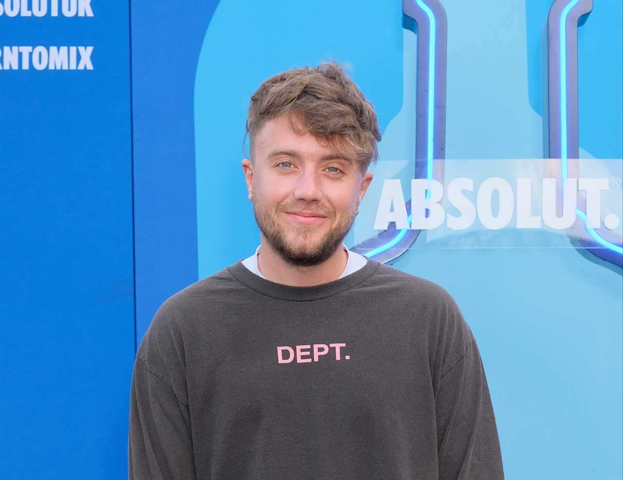 a man wearing a dept sweatshirt stands in front of an absolut sign