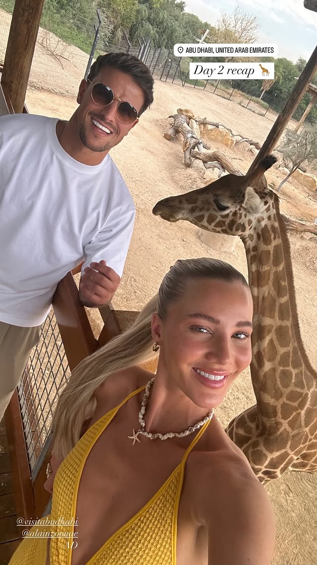 Luca Bish and Grace Jackson with a giraffe in Abu Dhabi.